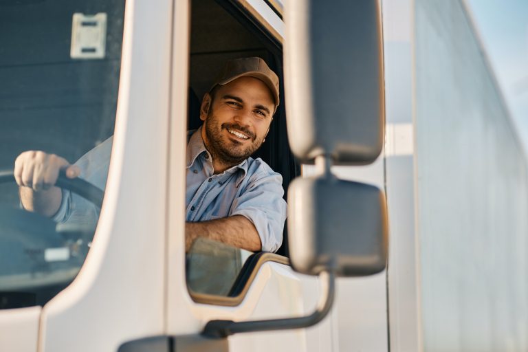 happy-truck-driver-looking-through-side-window-while-driving-his-truck-